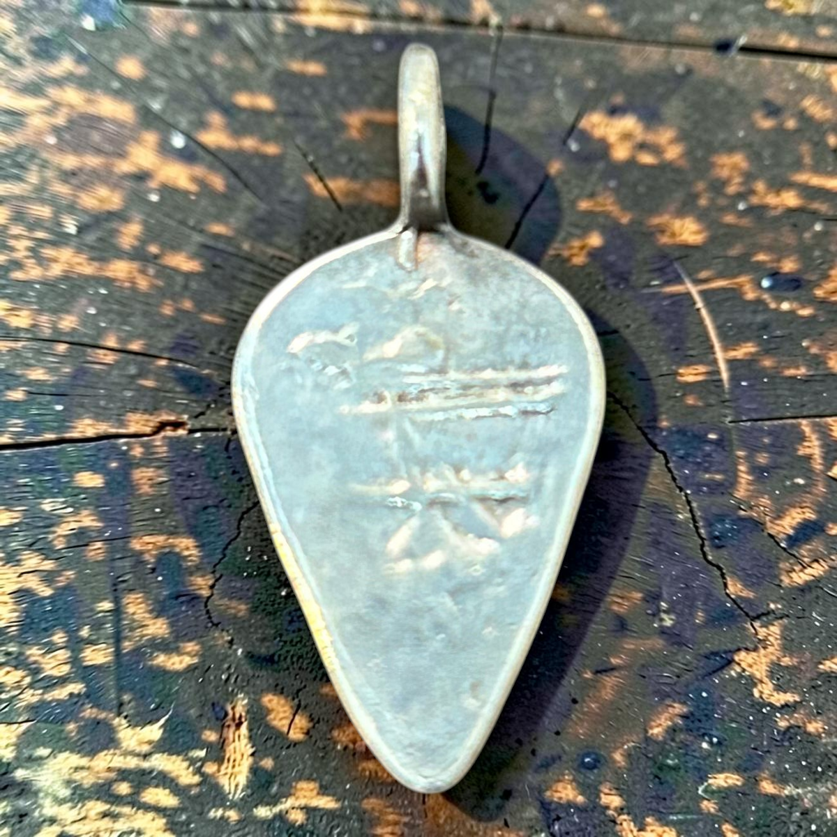 MILWORKS silver teardrop charm featuring a detailed Thunderbird engraving on a dark wooden surface