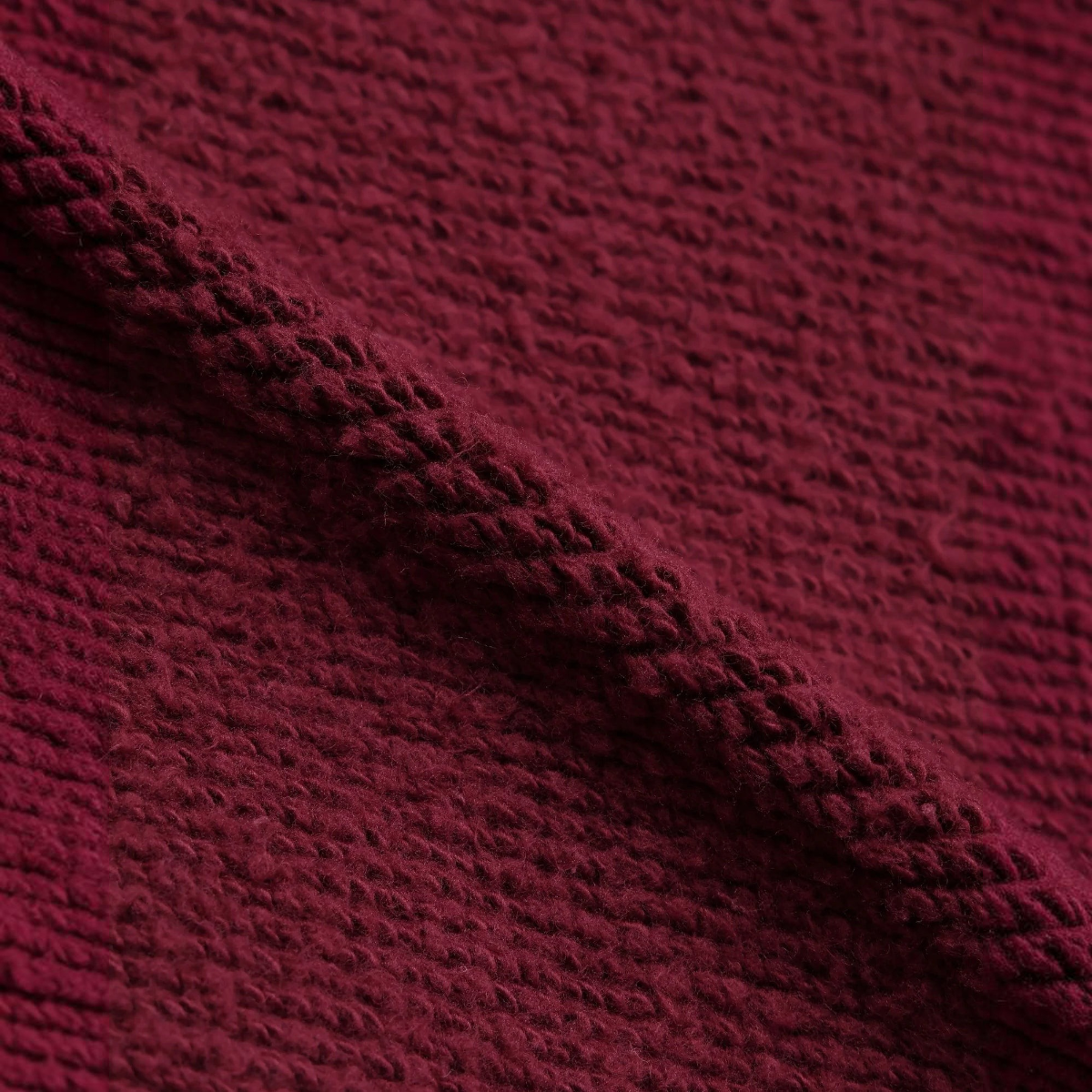 Close-up of MILWORKS burgundy double heavyweight French terry cotton fabric with visible soft loops and texture.