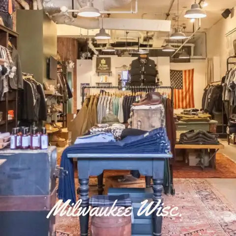 Blue wooden display table with stacked denim jeans and folded clothing items on top