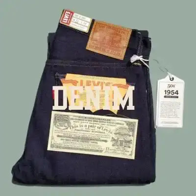 Dark blue denim jeans with multiple vintage-style tags, including a brown leather patch and white paper labels.