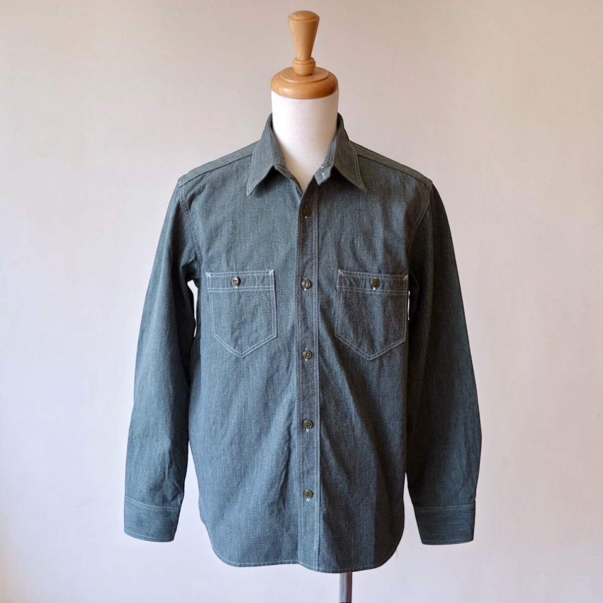 MILWORKS Atlas 6.5 oz. sage green Japanese selvedge salt and pepper chambray work shirt with cat's eye buttons.