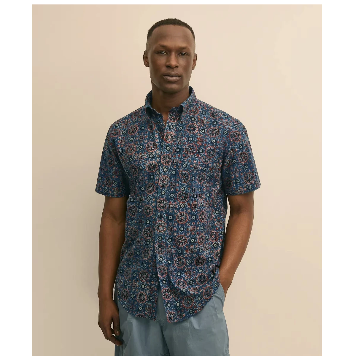 MILWORK blue cotton short sleeve shirt with a block print pattern in spice and orange tones. Model wears regular fit.