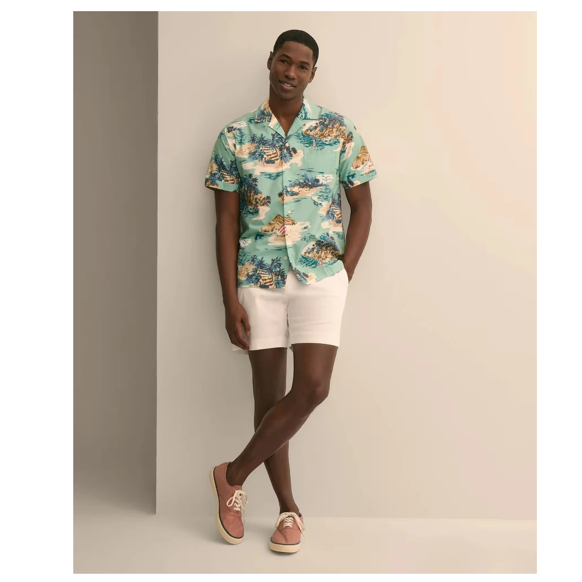 MILWORK blue 100% cotton camp collar shirt with island motif, worn by a man standing against a light grey wall.