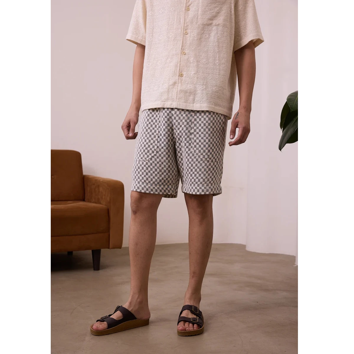 MILWORK Dipak black and white checkered crochet shorts with elastic waistband and pockets, worn by a man.