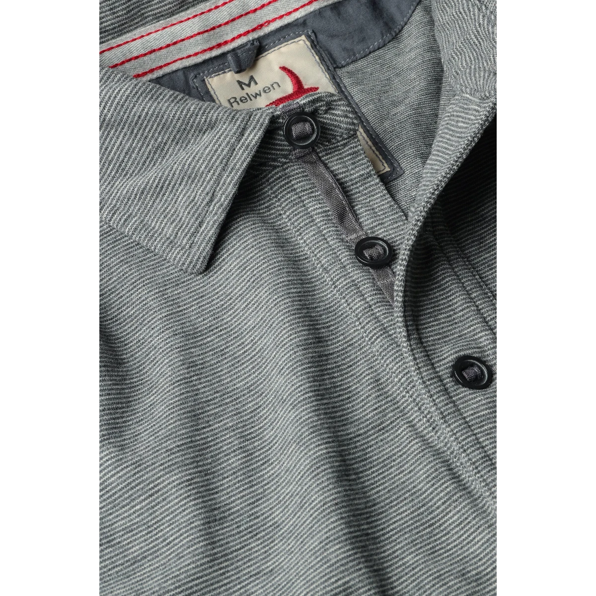 MILWORK Relwen Fineline Jersey Polo in dark grey and white striped knit fabric with button placket and red stitching detail.