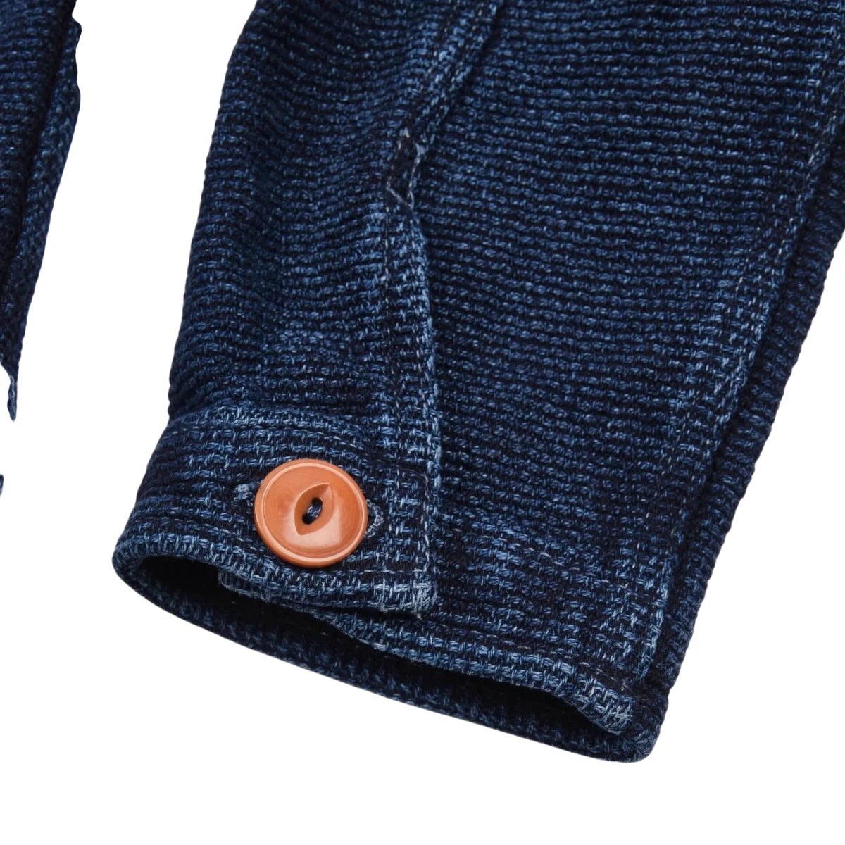 MILWORK Indigo Sashiko shirt cuff with a single orange button and visible stitching detail. 100% cotton.