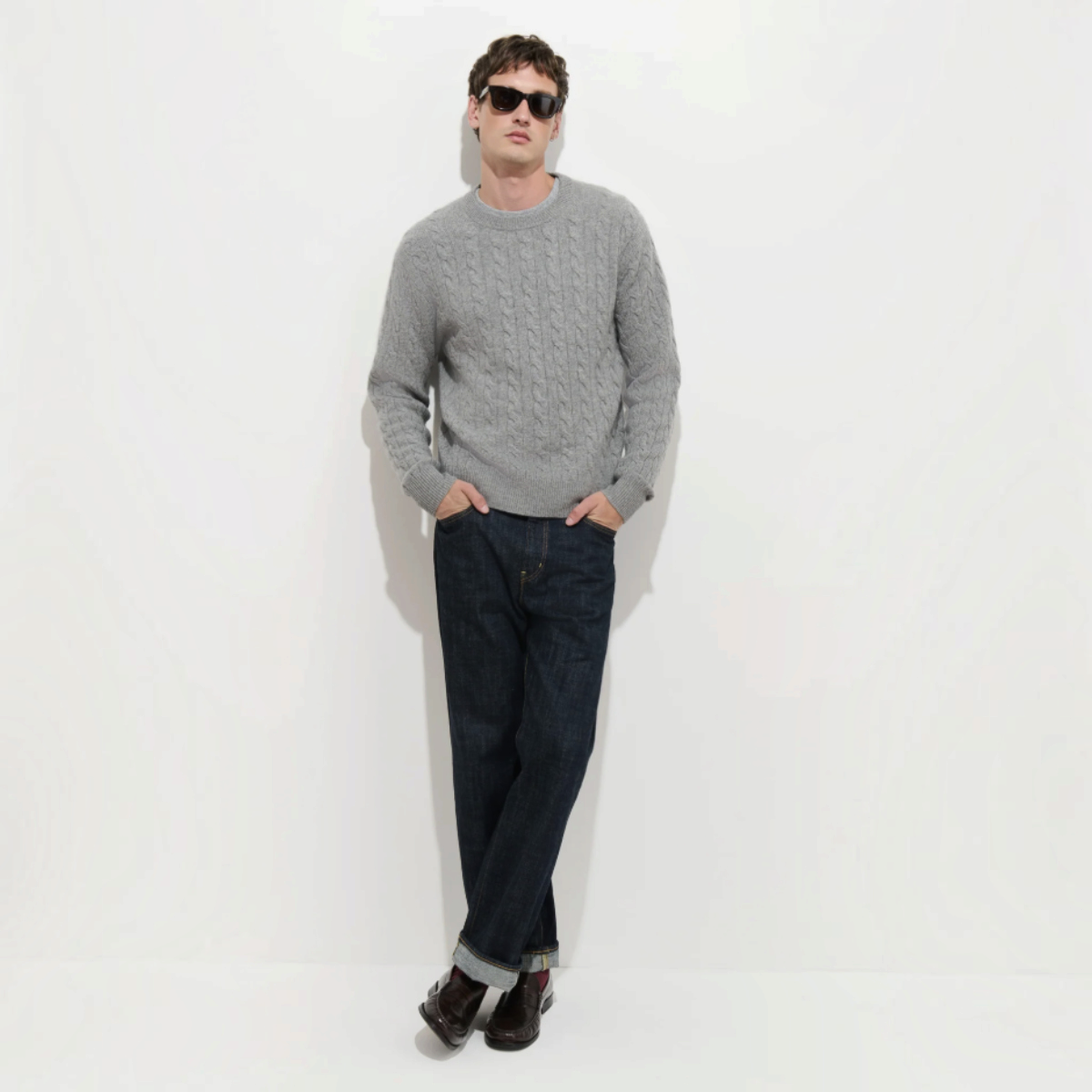MILWORKS model wearing a heather grey 100% cashmere cable knit sweater with dark denim jeans and sunglasses