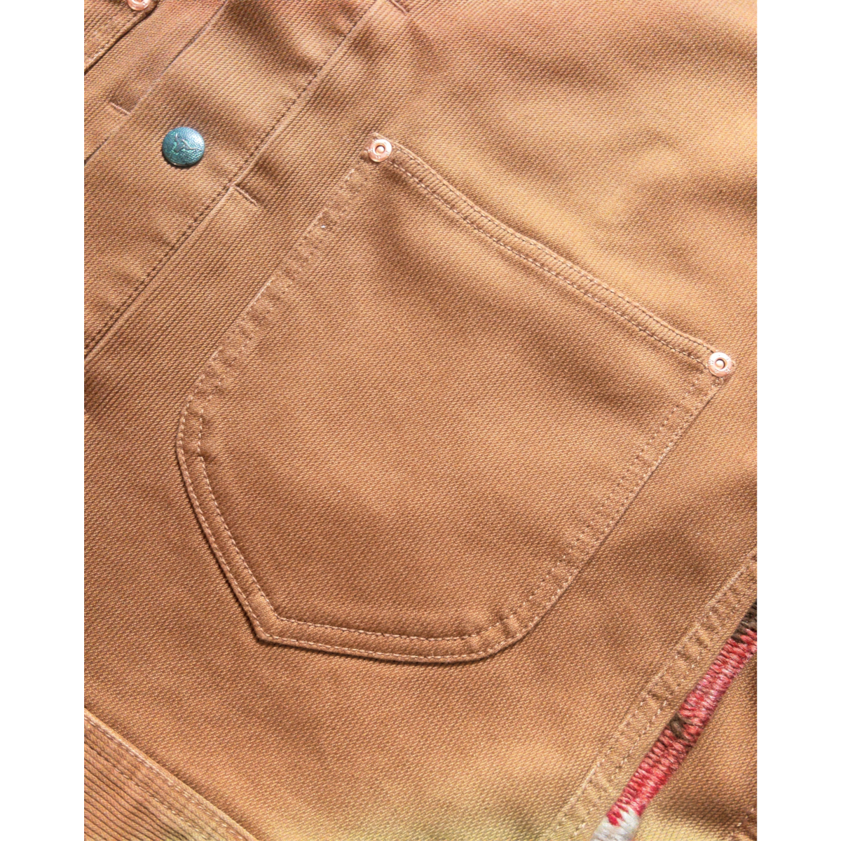Close-up of MILWORKS Bedford Cord Ranch Jacket in bay brown featuring an acorn pocket, copper rivets, and snap button.