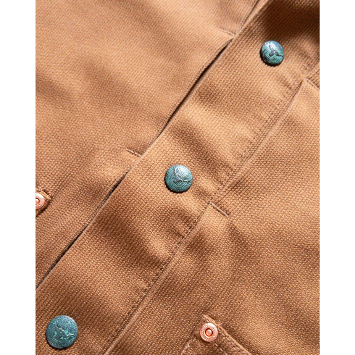 Close-up of MILWORKS Bedford Cord Ranch Jacket in bay brown featuring aged steer head snaps and raw copper rivets.
