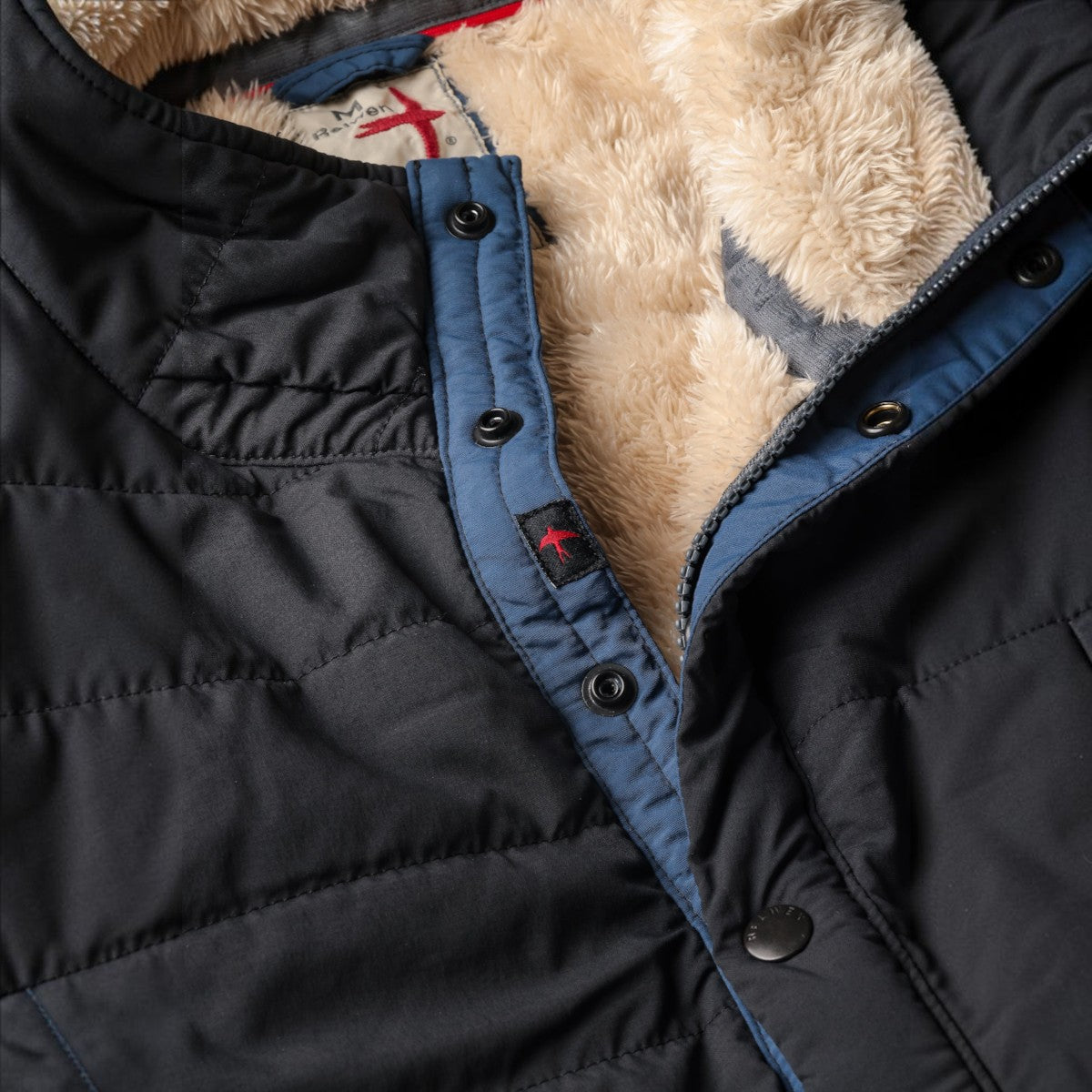 MILWORKS black quilted superfleece popover jacket with a soft beige faux fur lining and snap button placket detail.