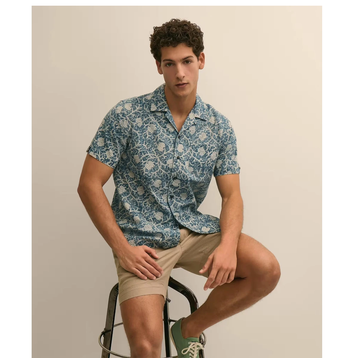 MILWORKS blue and white block print 100% cotton camp collar short sleeve shirt on a man sitting on a stool.