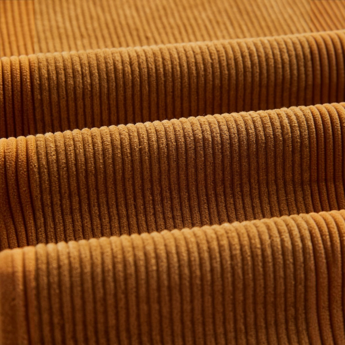 Close-up of MILWORKS corduroy trousers fabric in a warm autumn brown shade with soft vertical ridges