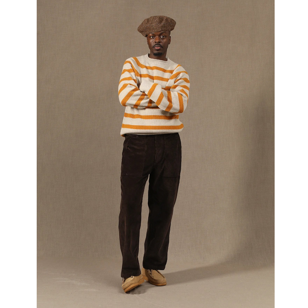 MILWORKS model wearing brown corduroy fatigue pants, striped sweater, and beret against a neutral studio backdrop.