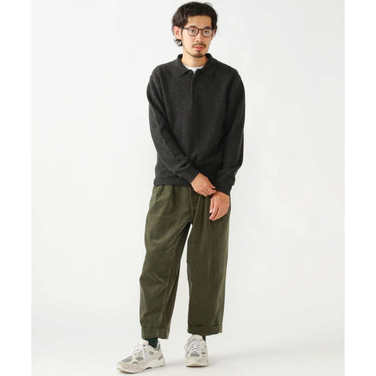 A model wearing a MILWORKS charcoal 9-gauge wool knit polo shirt with olive corduroy trousers and sneakers.