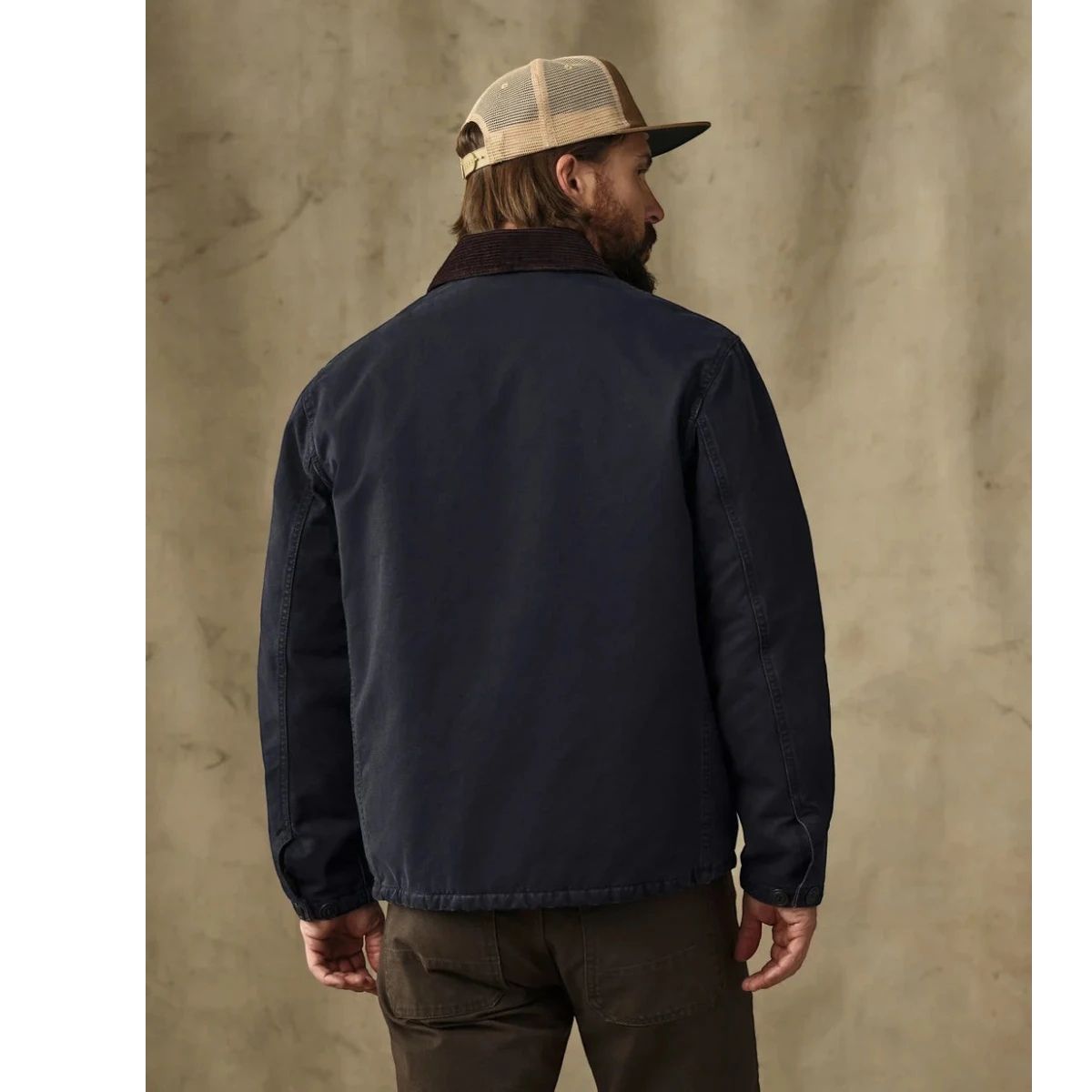 Back view of a man wearing a MILWORKS dark navy insulated canvas outfitter jacket with a corduroy collar