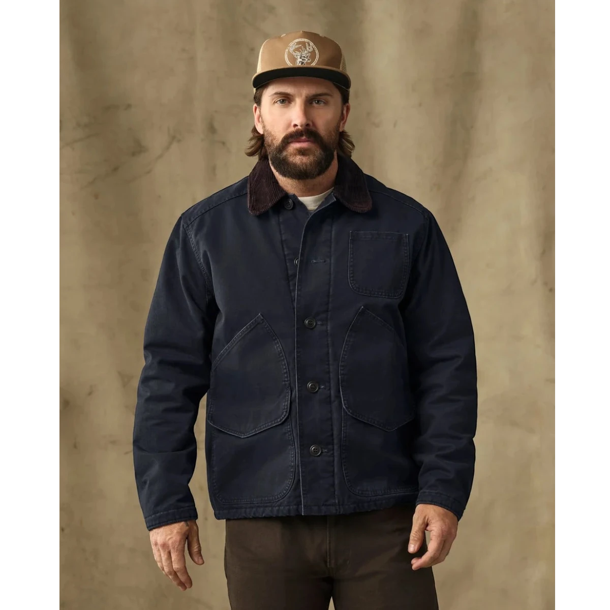 MILWORKS model wearing a dark navy insulated canvas outfitter jacket with a corduroy collar and button-front closure.
