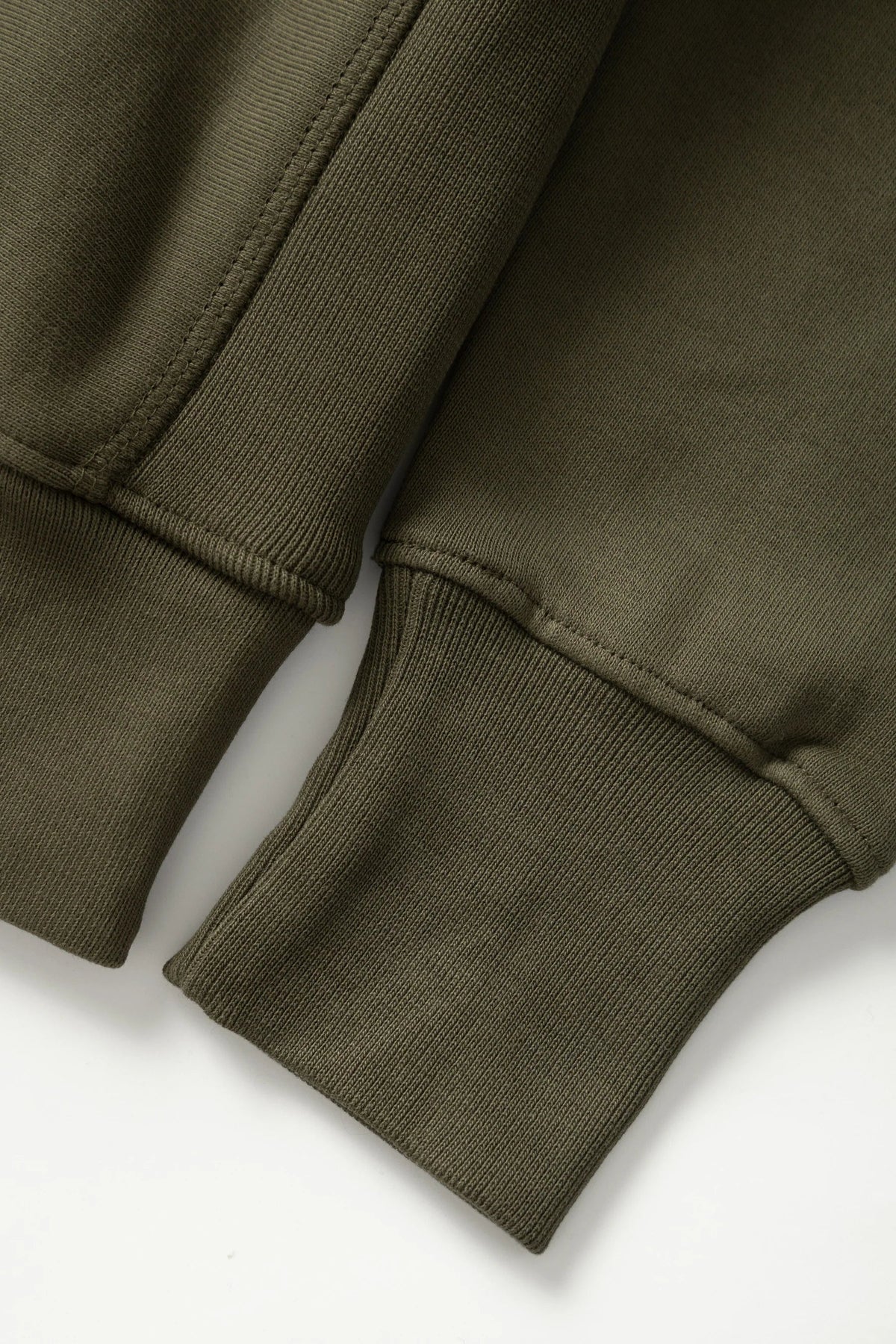 MILWORKS dark olive heavyweight organic cotton rugby shirt showing detailed ribbed cuffs and side panel stitching.