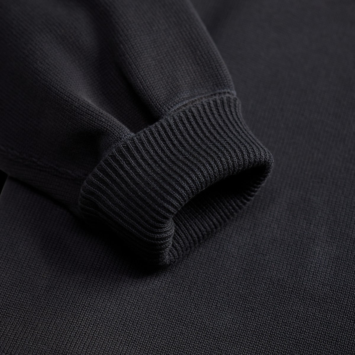 Close-up of the ribbed cuff on a MILWORKS faded navy cotton-blend fleece half zip sweatshirt.