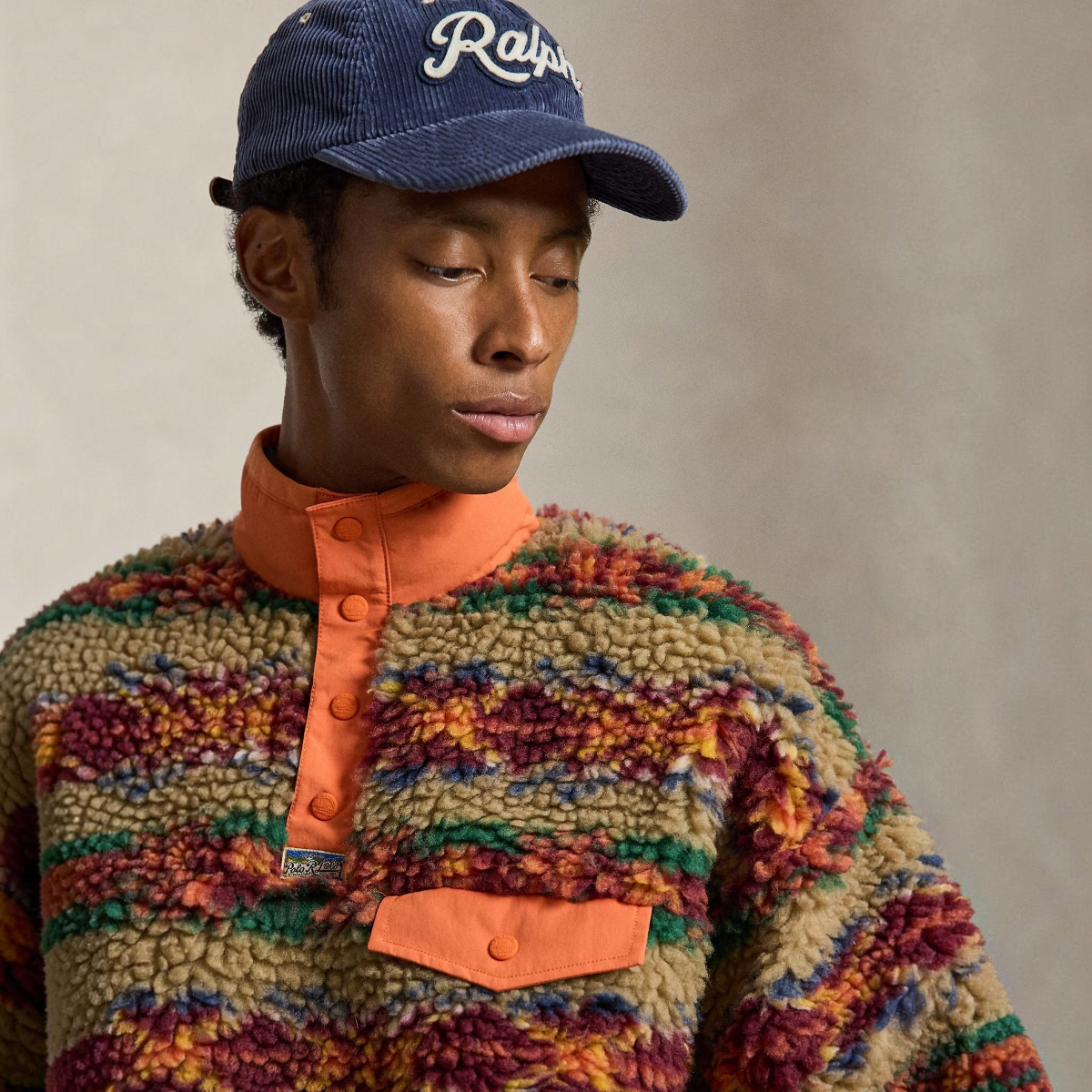 MILWORKS model wearing a high-pile fleece pullover with a Red Rock Fairisle print, mockneck, and orange woven details.