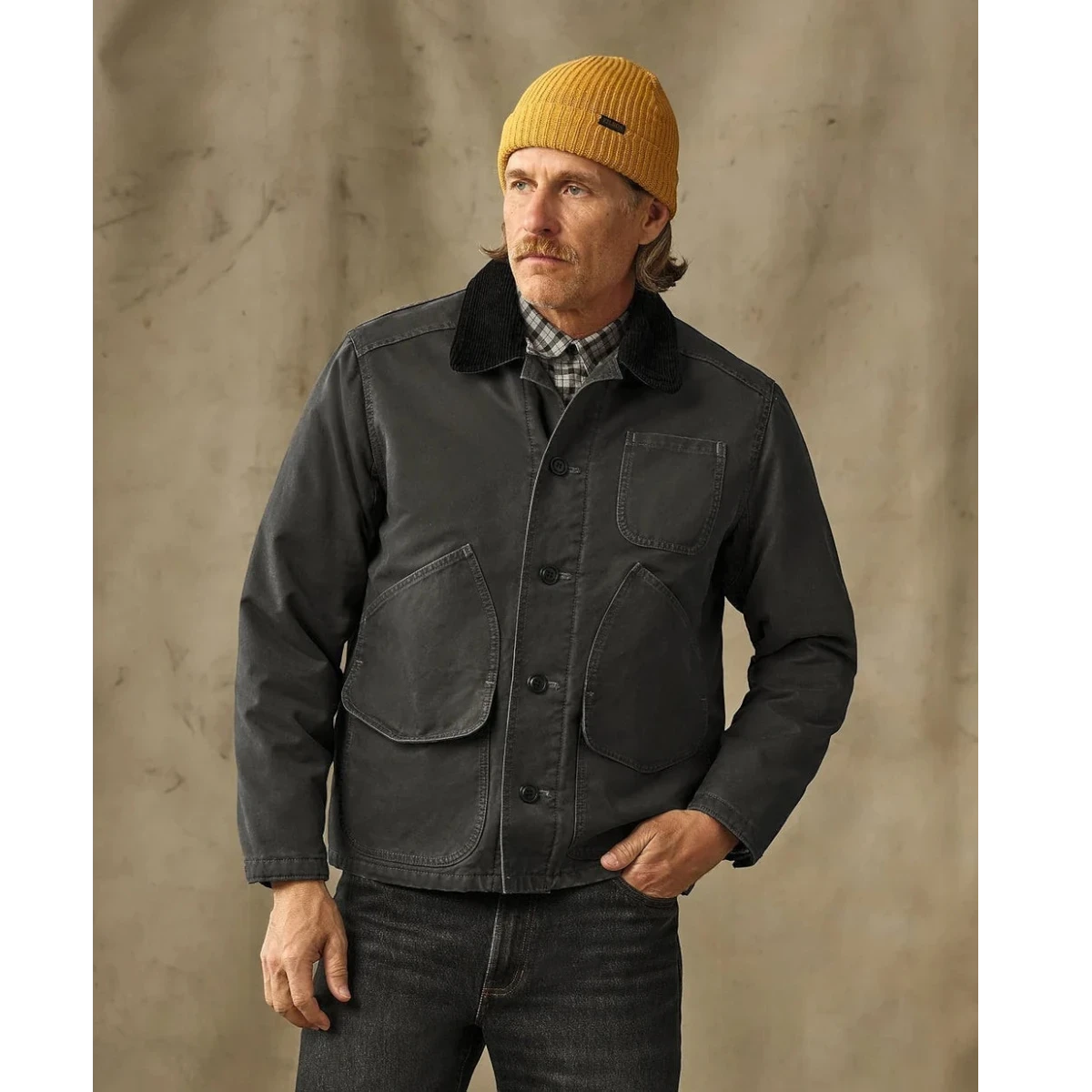 MILWORKS Filson insulated canvas outfitter jacket in peat green with a corduroy collar worn by a man in a beanie.