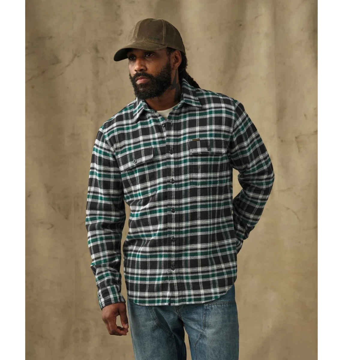 MILWORKS model wearing a Filson black and green plaid flannel work shirt with button-flap chest pockets