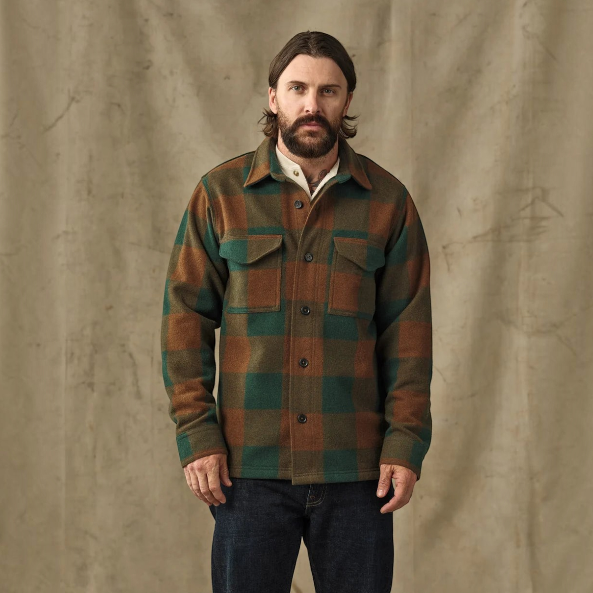 MILWORKS Filson wool jac-shirt in bronze and green plaid with button-down front and chest pockets on a bearded man.