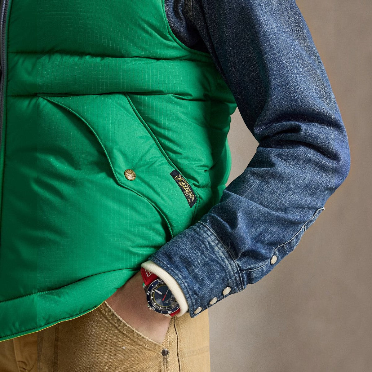 MILWORKS green ripstop down vest with leather yoke detail and snapped pocket, worn over a denim shirt.