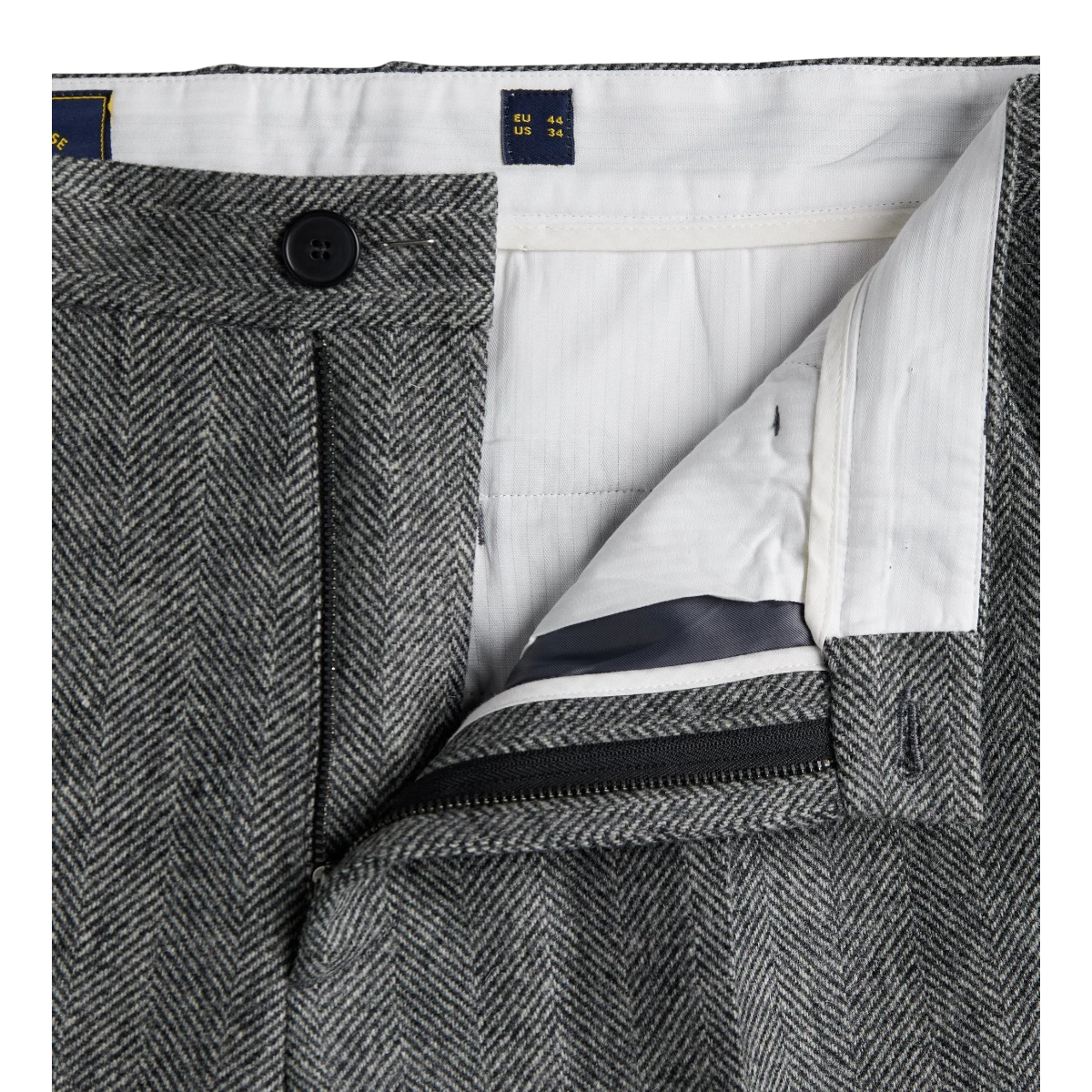 MILWORKS grey herringbone virgin wool single pleat trousers featuring a button fly and white interior lining