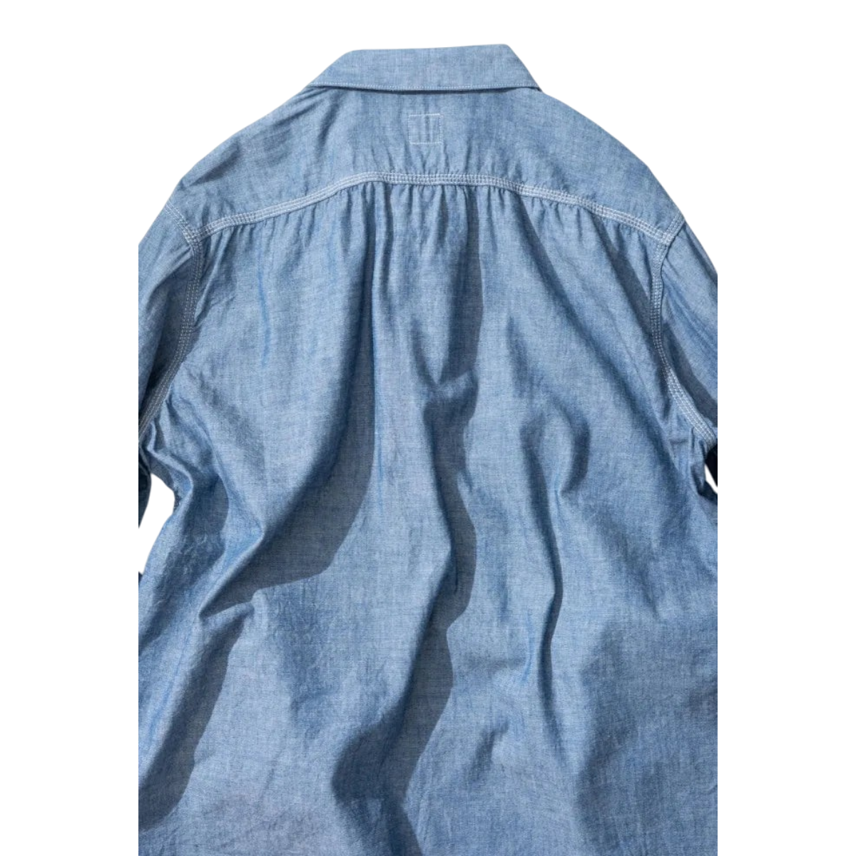 Back view of MILWORKS Ordinary Fits indigo chambray work shirt featuring a boxy fit and yoke detailing.