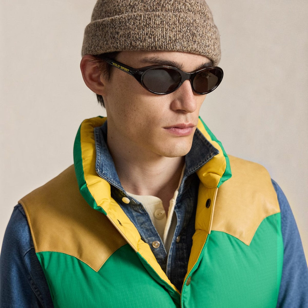 MILWORKS model wearing a green and yellow ripstop down vest with a brown leather Western yoke and mockneck collar.
