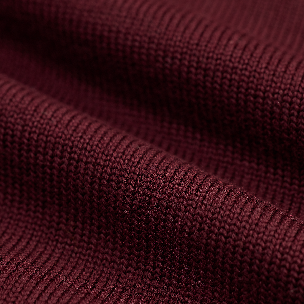 Close-up of MILWORKS maroon wool sweater fabric showing the detailed knit texture and deep red color.