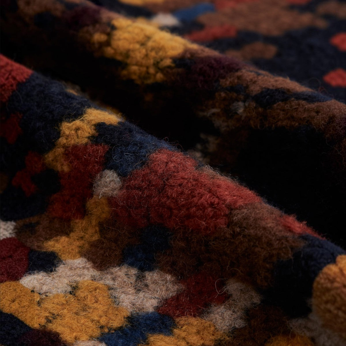 Close-up of the MILWORKS Mia wool blend overshirt fabric featuring a textured multi-colored geometric pattern.