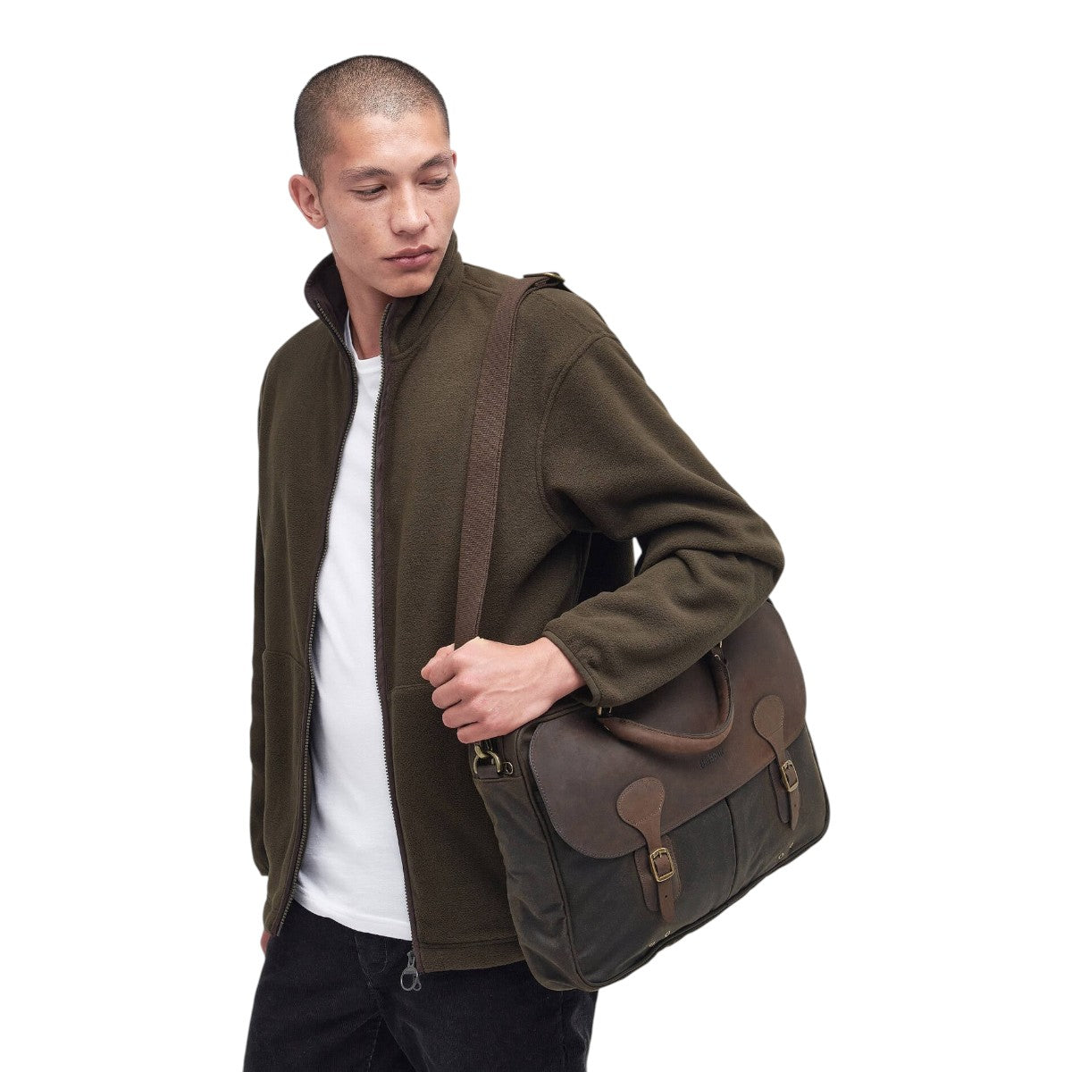 MILWORKS model carrying an olive waxed cotton and leather briefcase with antique brass hardware and shoulder strap.