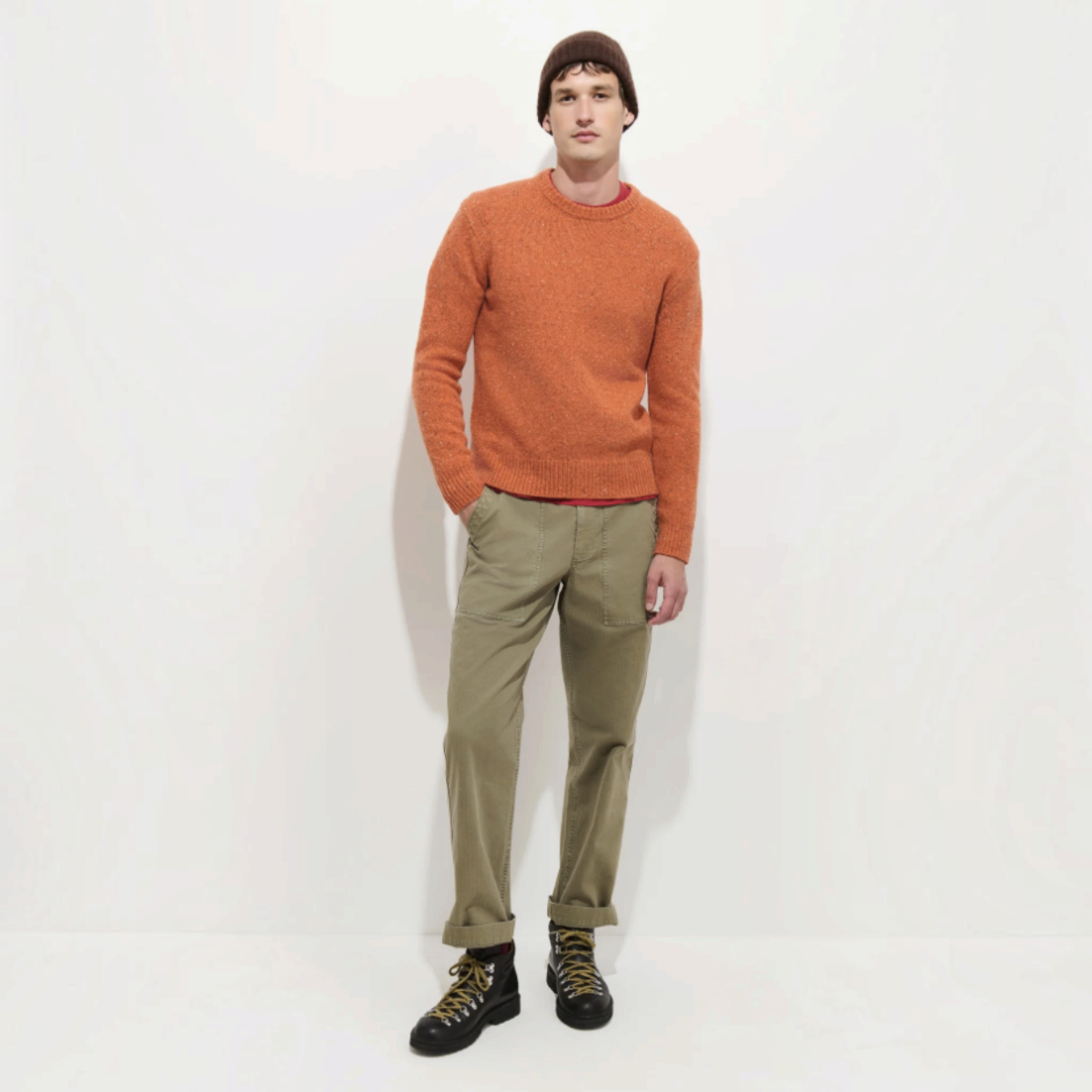 MILWORKS model wearing an orange Donegal crew neck sweater made from a wool and alpaca blend with olive trousers.