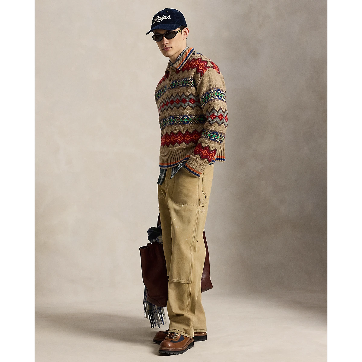 MILWORKS model wearing a tan Polo Ralph Lauren Fair Isle sweater polo with a plaid shirt, tan pants, and a cap.