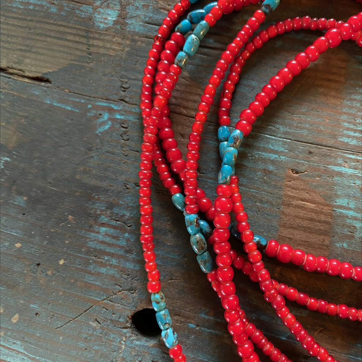MILWORKS red glass White-Heart and blue turquoise bead necklace on a rustic wooden surface