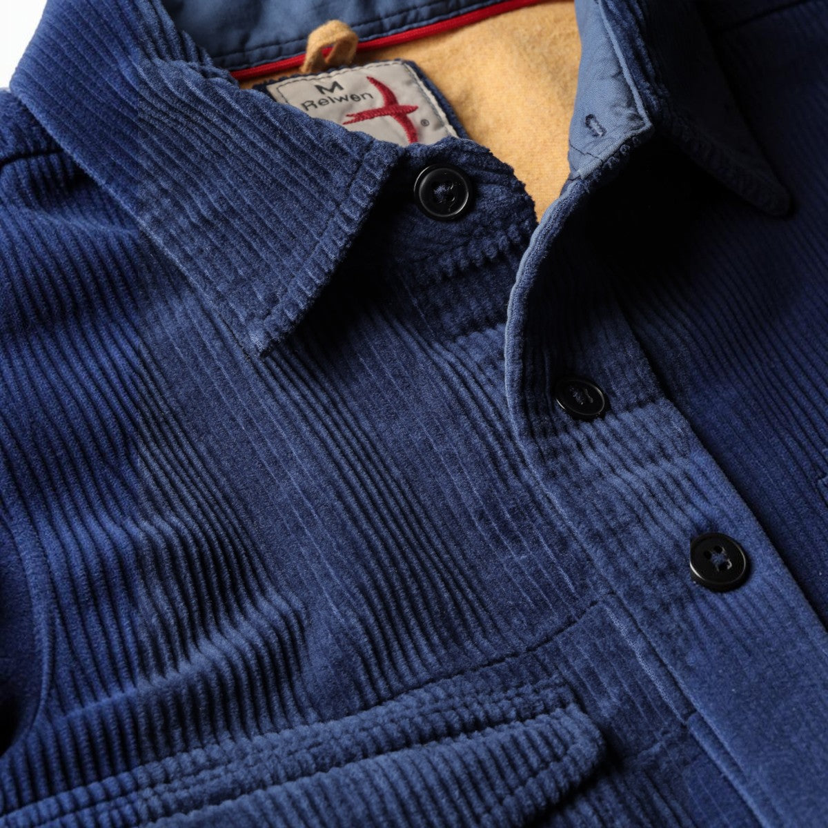 MILWORKS Relwen corduroy workshirt in admiral blue with a soft yellow interior lining and button-down collar.