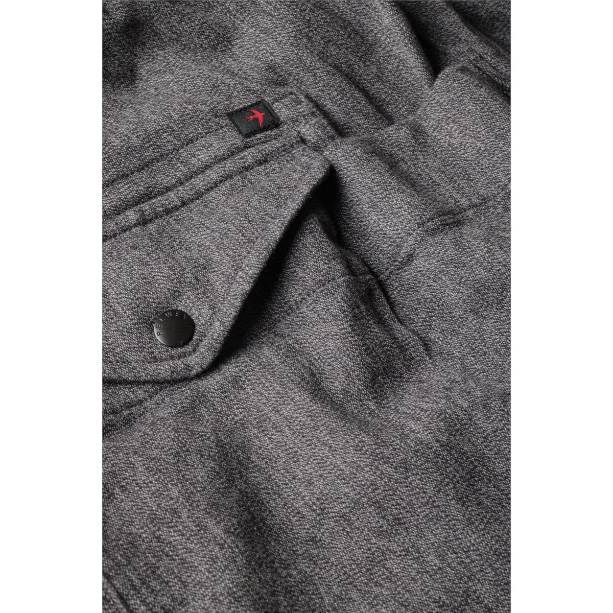 MILWORKS Relwen charcoal covert twill utility pant featuring a flap pocket with a branded button and red logo tab.