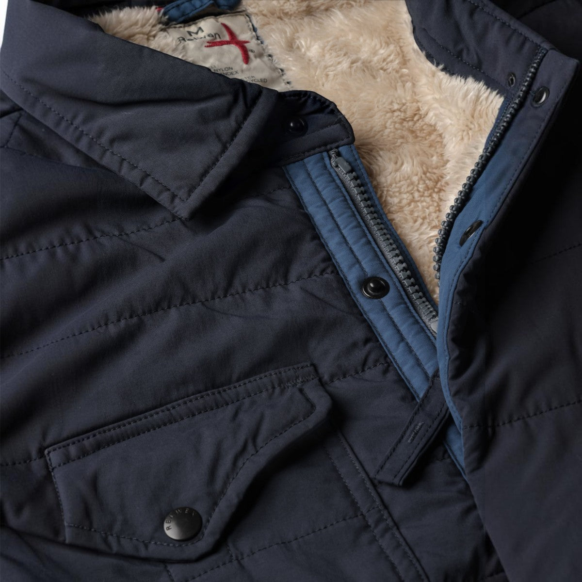 MILWORKS Relwen navy quilted jacket featuring a soft cream-colored fleece lining and snap button closure.