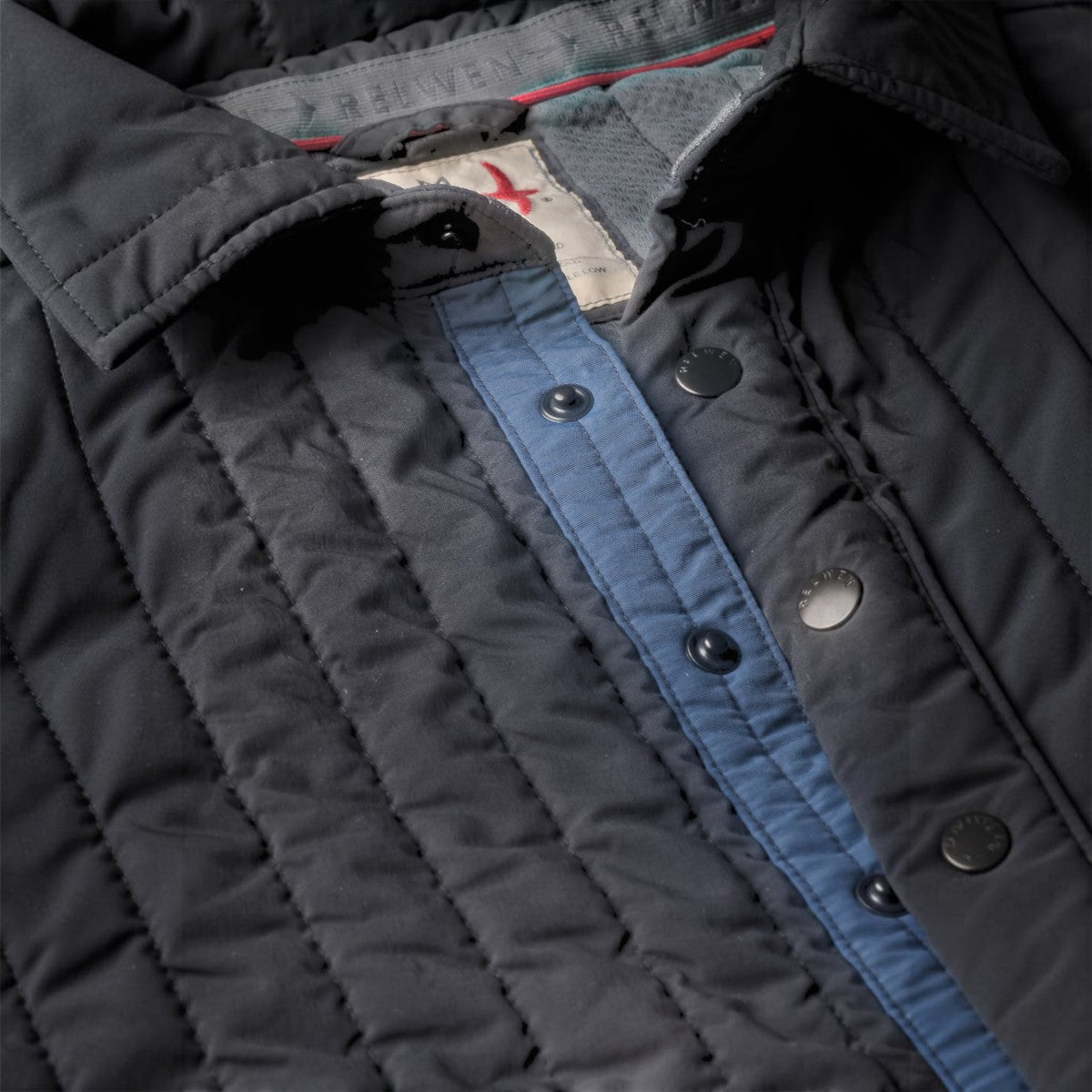 MILWORKS Relwen Polo Jack in midnight navy with quilted fabric, snap button placket, and contrasting blue trim.