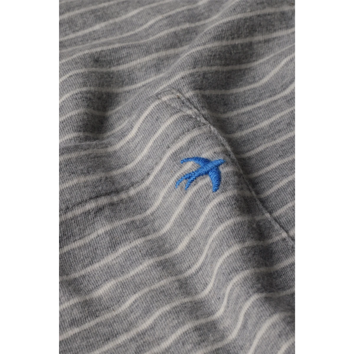 Close-up of MILWORKS Relwen ringspun long sleeve pocket tee in grey and white stripes with a blue bird embroidery