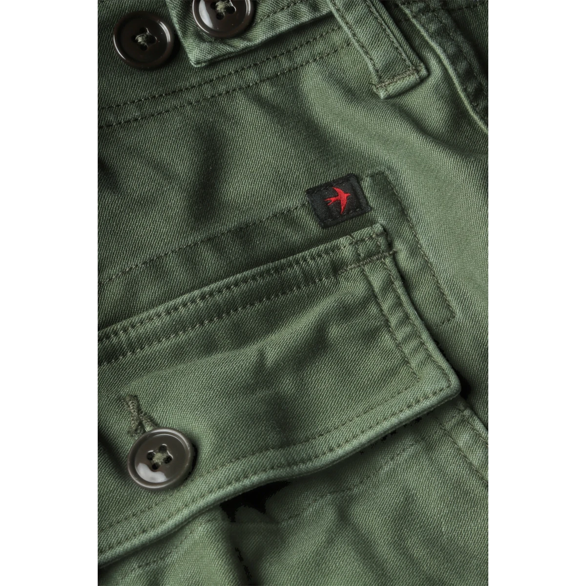 Close-up of MILWORKS Relwen Supply Pant in army green featuring a buttoned cargo pocket and small red bird logo tag.