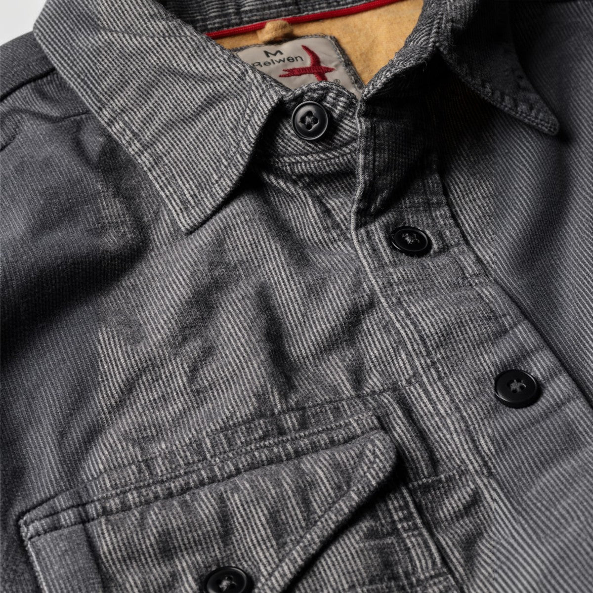 MILWORKS Relwen Utility Workshirt in steel grey microwale corduroy with black buttons and a soft tan interior lining.