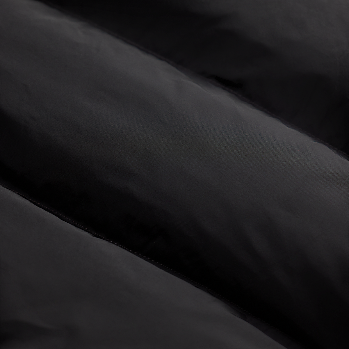 Close-up detail of the black quilted nylon fabric on a MILWORKS RRL cowhide shearling coat.