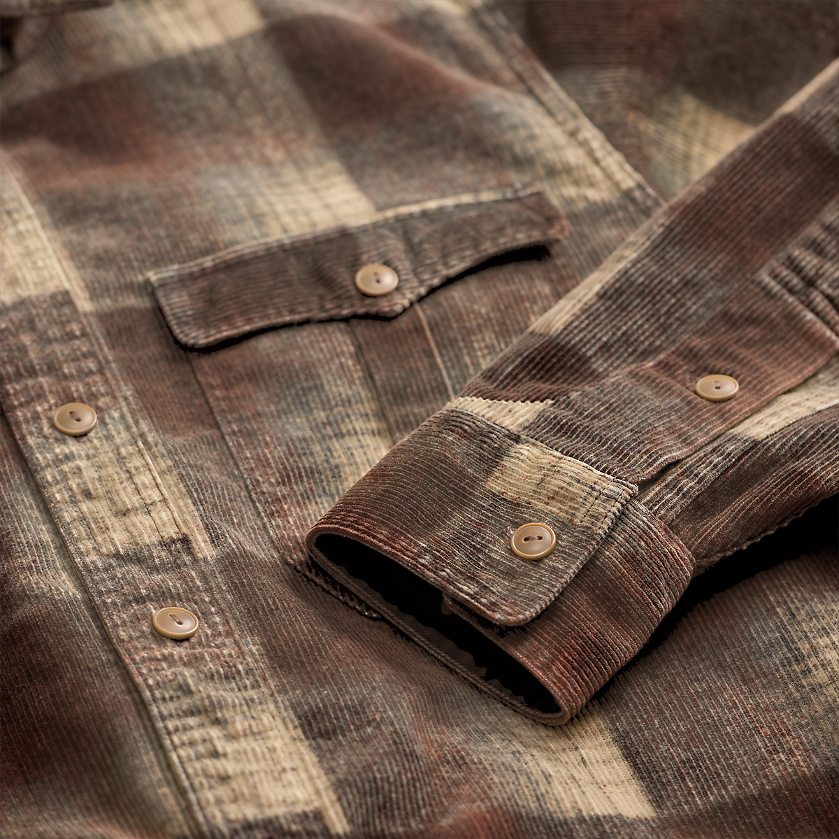 Close-up of a MILWORKS RRL corduroy long sleeve sport shirt in brown and grey plaid with buttoned cuffs and pocket.