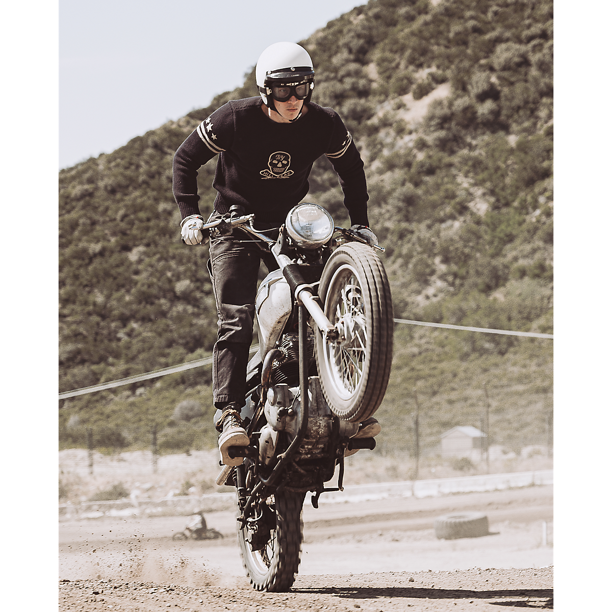 MILWORKS RRL dark navy long sleeve pullover sweater with graphic detail worn by a motorcyclist doing a wheelie