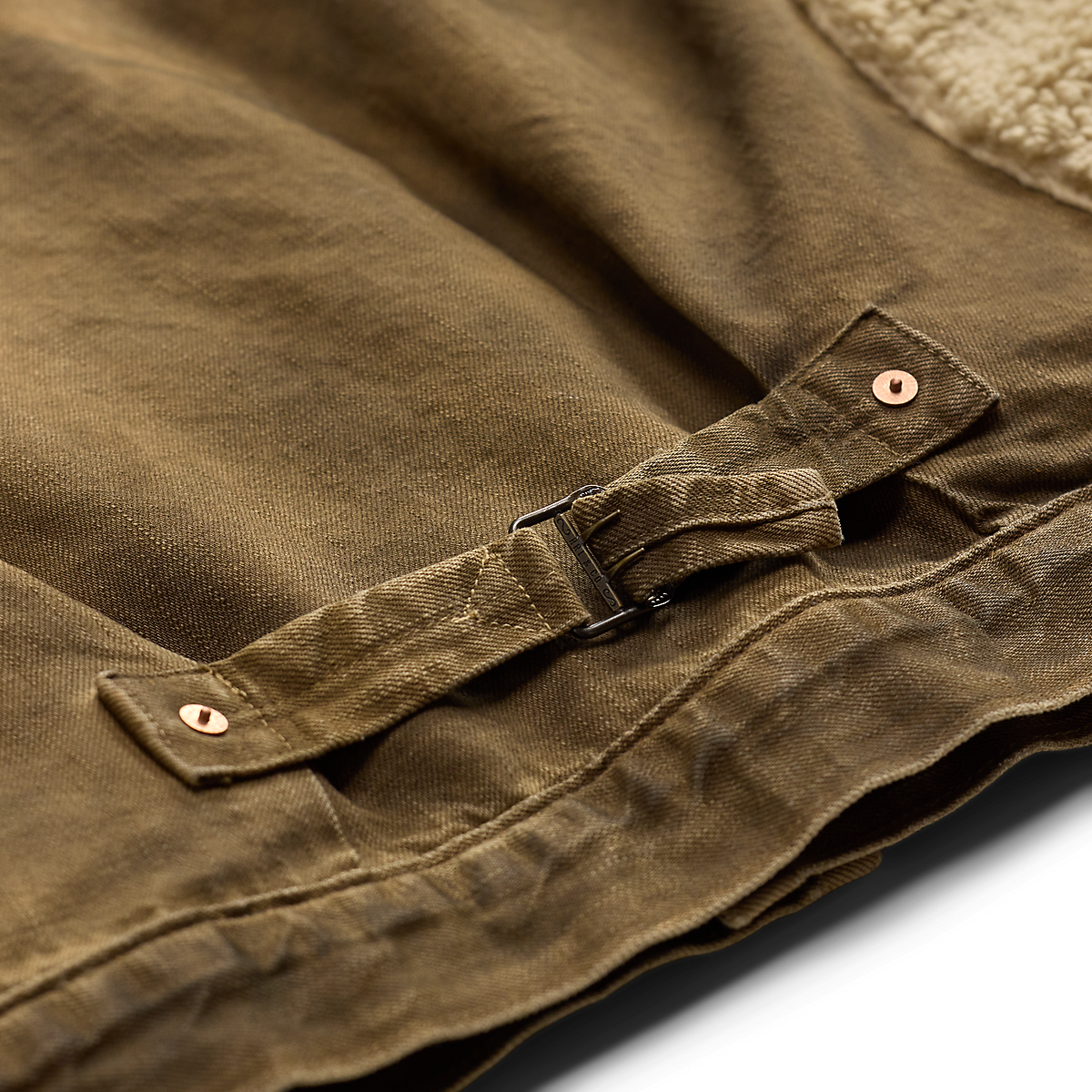 Close-up of MILWORKS RRL vintage brown denim jacket featuring a side cinch buckle and cream shearling lining.