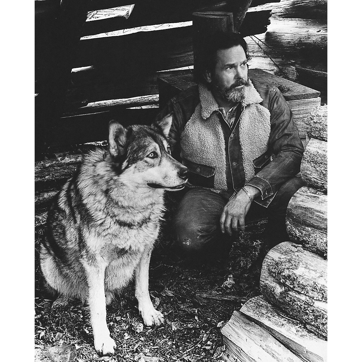 MILWORKS RRL vintage brown denim jacket with shearling lining worn by a bearded man sitting outdoors with a wolf