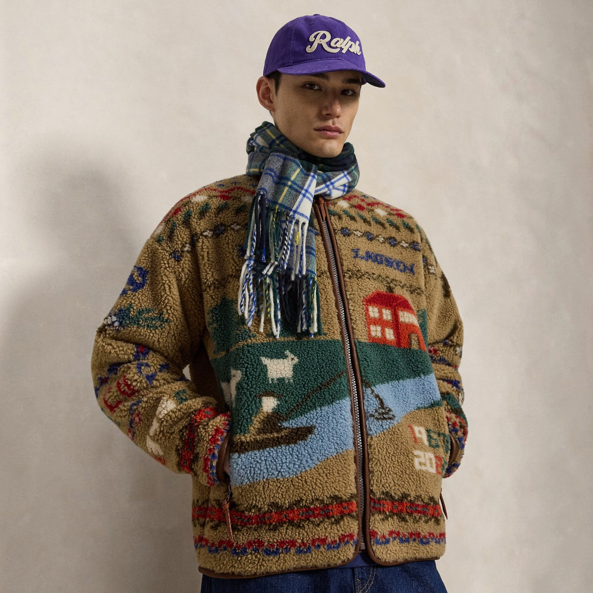 A model wearing a MILWORKS Scenic Pile Fleece Jacket in Montana Khaki with a scenic landscape and geometric motifs.