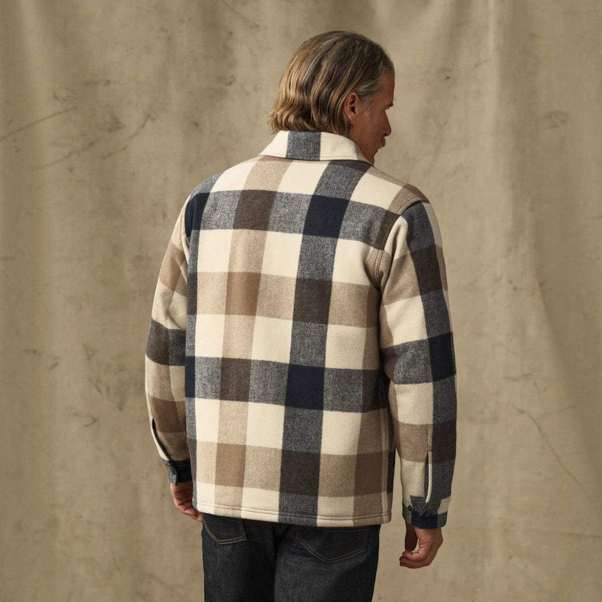 Back view of a man wearing a MILWORKS Spokane insulated wool-blend jac-shirt in a cream and navy plaid pattern.